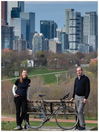 Photo of Dr. Marie Faughnan with her colleague Dr. Robert Stewart outdoors next to a park bench and bicycle in June 2019.